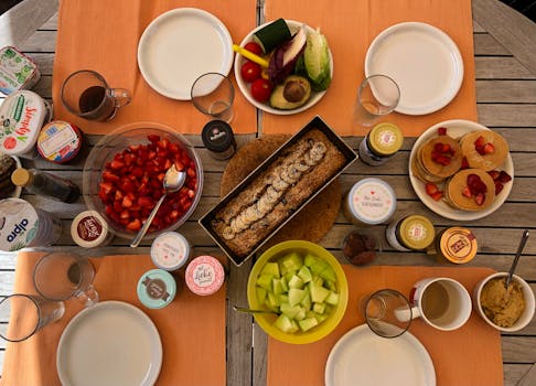 Table dressée avec un panier gourmand sans gluten, des fruits frais, des plats variés et des boissons.